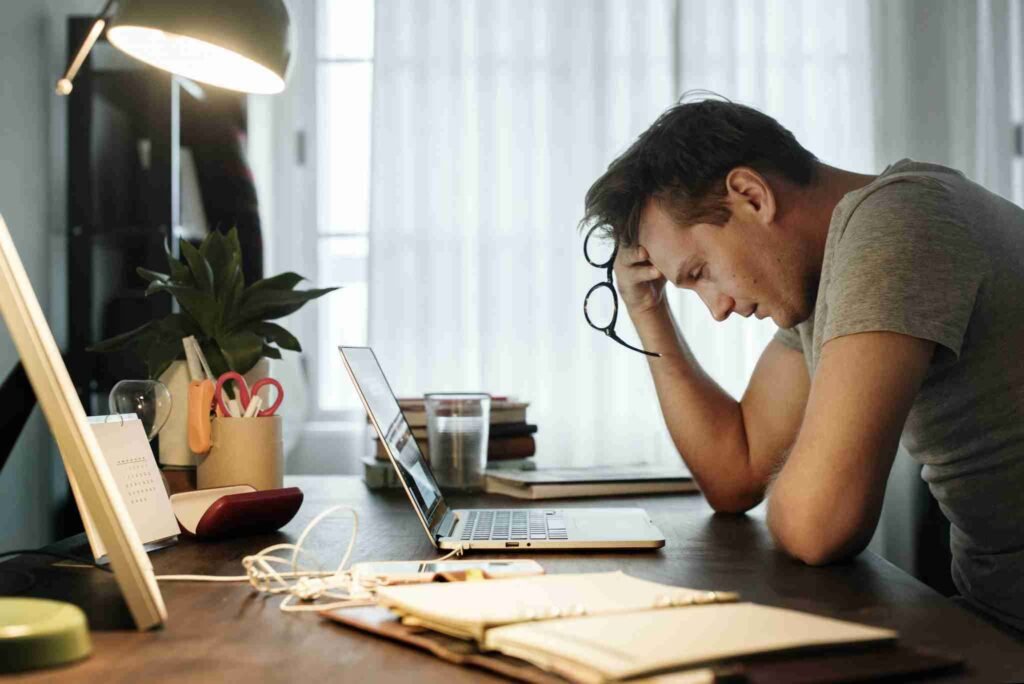 Man-sits-at-his-desk-looks-at-bills-holds-his-head